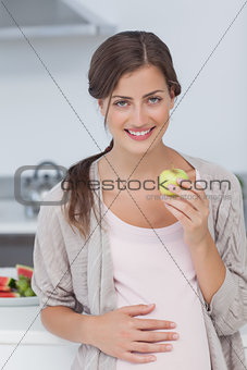 Pregnant woman holding a green apple