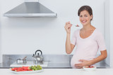Pregnant woman eating cereal in the kitchen
