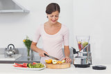 Pregnant woman cutting fruits in the kitchen