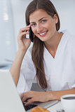 Cheerful woman phoning and using her laptop