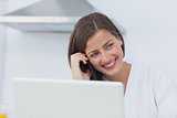Cheerful woman on the phone using her laptop