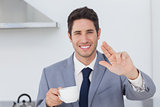 Cheerful businessman waving at someone in the kitchen