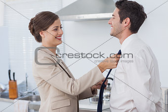 Woman helping her husband to tie his tie