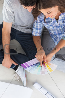 Woman pointing at color charts sitting in her new house