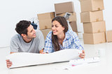 Couple lying on the floor and holding house plans