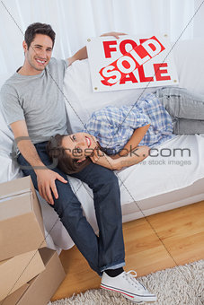 Man in his new house holding a sign with sold written on it