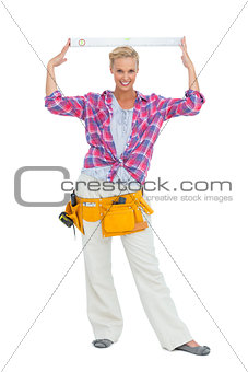 Blonde woman standing while putting a spirit level on her head