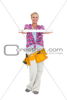 Woman holding a spirit level smiling at camera