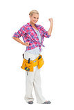 Happy blonde woman tensing arms wearing tool belt