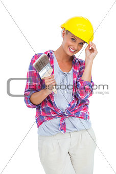 Handy woman touching her helmet and holding paintbrush