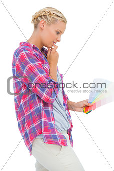 Concentrated young woman looking at color charts
