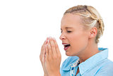 Blonde woman sneezing with hands in front of her face