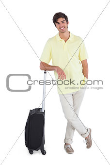 Smiling man standing with his suitcase