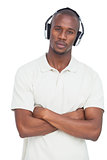 Man with arms crossed listening to music