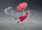 Attractive woman flying with a broken umbrella