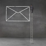 Businessman drawing a giant envelope and standing on a giant ladder