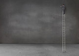 Businessman standing on a giant ladder in an empty room