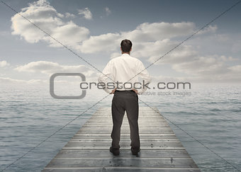 Businessman standing on a bridge with hands on hips
