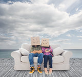 Couple sitting on couch with cardboard over their head