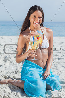 Smiling woman wearing sarong and holding cocktail