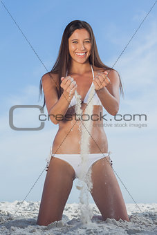 Woman in bikini playing with sand