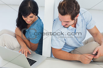 Woman showing something on laptop at her boyfriend