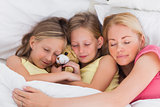 Woman sleeping in bed with her cute children