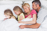 Parents sleeping in bed with their twins