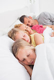 Parents sleeping with their twins in bed