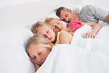 Parents sleeping with their children in bed