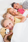 Young girl awake next to her sleeping family