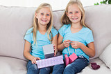 Cute twins unwrapping birthday gift sitting on a couch