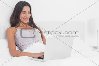 Woman using her laptop in bed