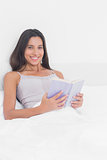 Portrait of a woman reading a lilac book in bed