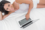 Portrait of a woman using her laptop lying in bed