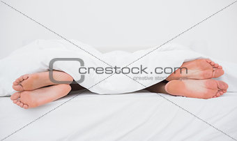 Feet of a couple on their opposite sides in bed
