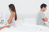 Couple sitting back to back on bed