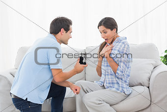 Man on bended knee offering an engagement ring to his partner