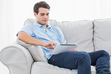 Man using his tablet sitting on a couch