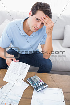 Fearful man doing his accounts with a calculator