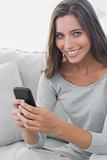 Woman texting while she is sat on a sofa