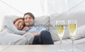 Couple resting on a couch with flutes of champagne