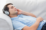 Man enjoying music lying on a couch