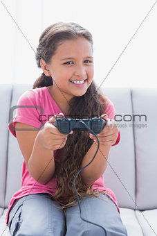 Little girl playing video game on sofa