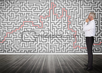Thoughtful businessman looking at a maze on a wall