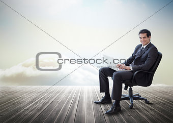 Handsome businessman sitting on a swivel chair and using his laptop