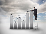 Businessman standing on a ladder drawing a chart