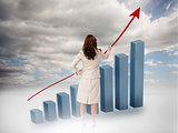 Businesswoman drawing a red arrow over a growing chart