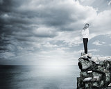 Thoughtful businessman standing at the edge of a cliff