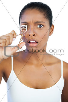 Shocked woman using curler for her eyelash
